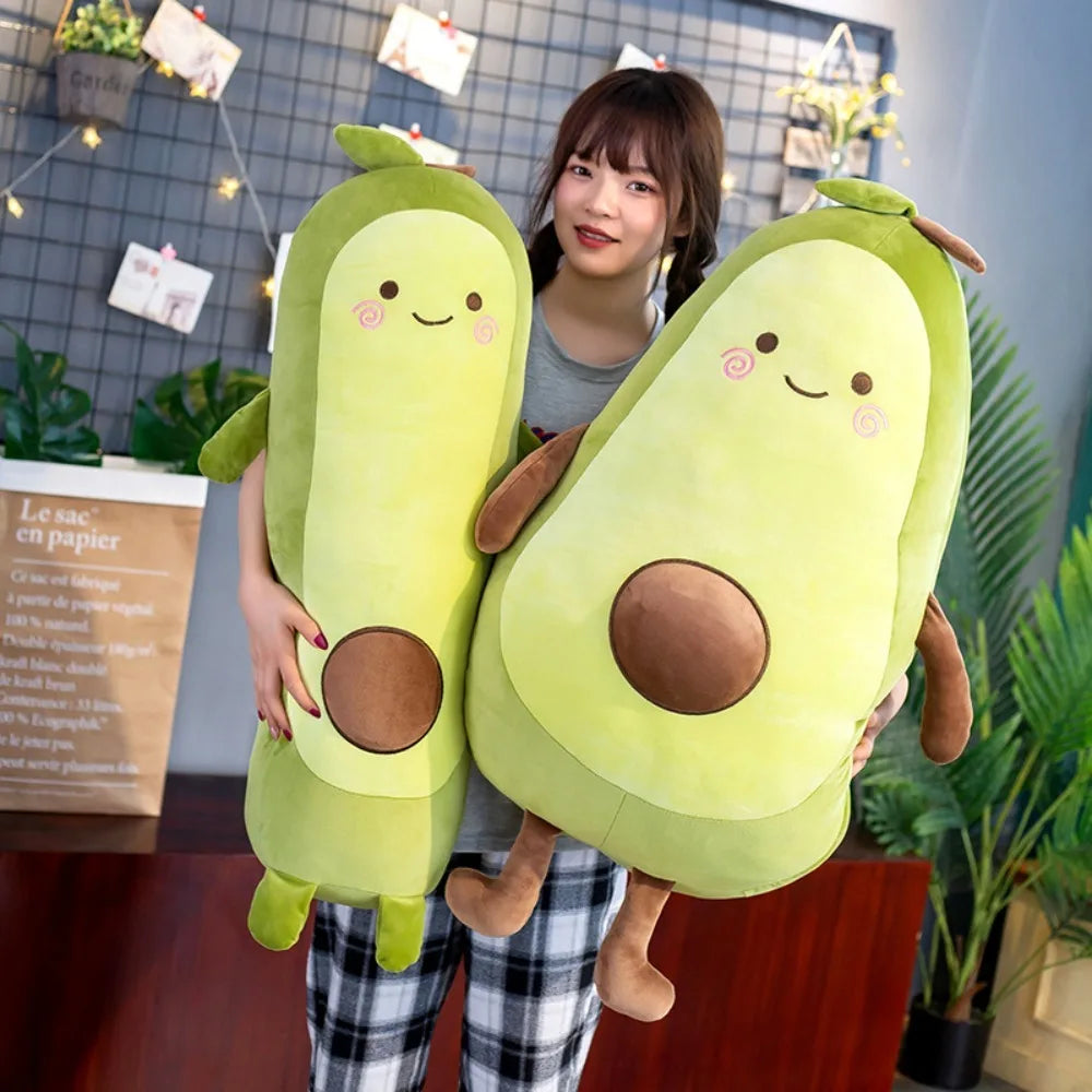 Person holding two kawaii plush avocado toys in a room with plants and a wall display.