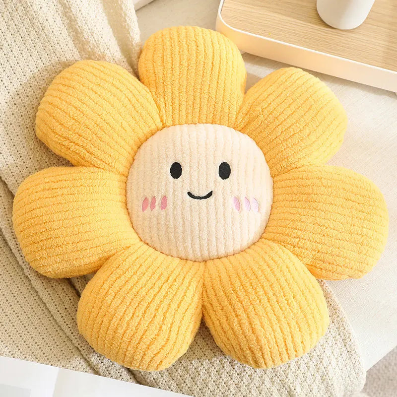Yellow flower-shaped kawaii plush toy with a smiling face on a beige surface.
