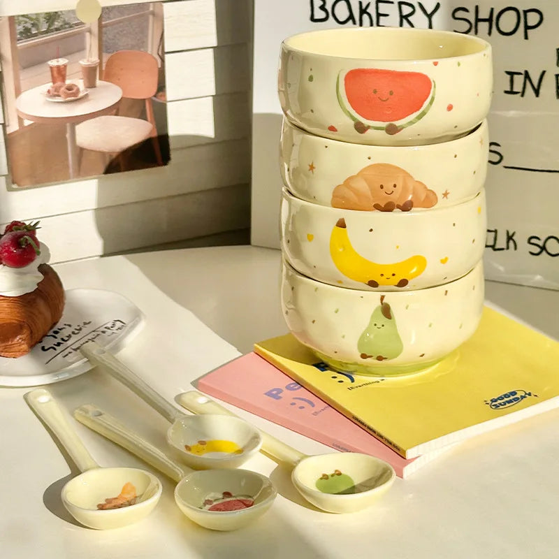 Four kawaii bowls stacked on a table with spoons next to them