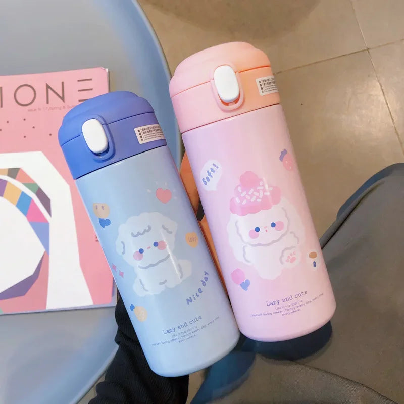 Two cartoon-themed kawaii water bottles, one blue and one pink, on a surface with a magazine in the background.