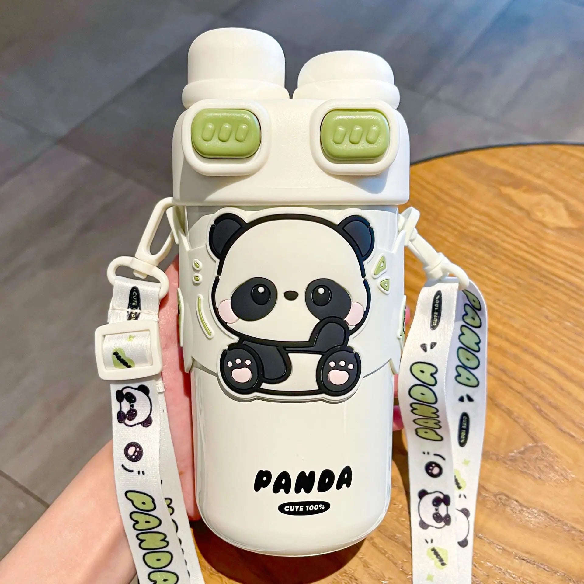 White kawaii water bottle with panda design and green accents, held by a person.