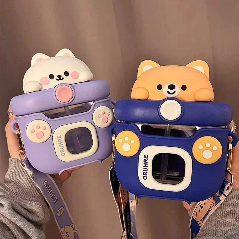 Two camera shaped kawaii water bottles with bear designs, one purple and one blue, held by a person.