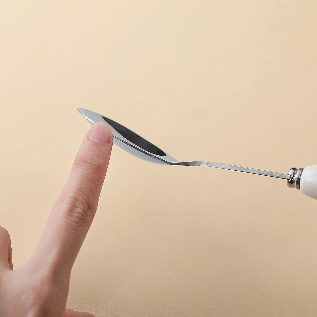 Small kawaii utensil held by a finger against a beige background