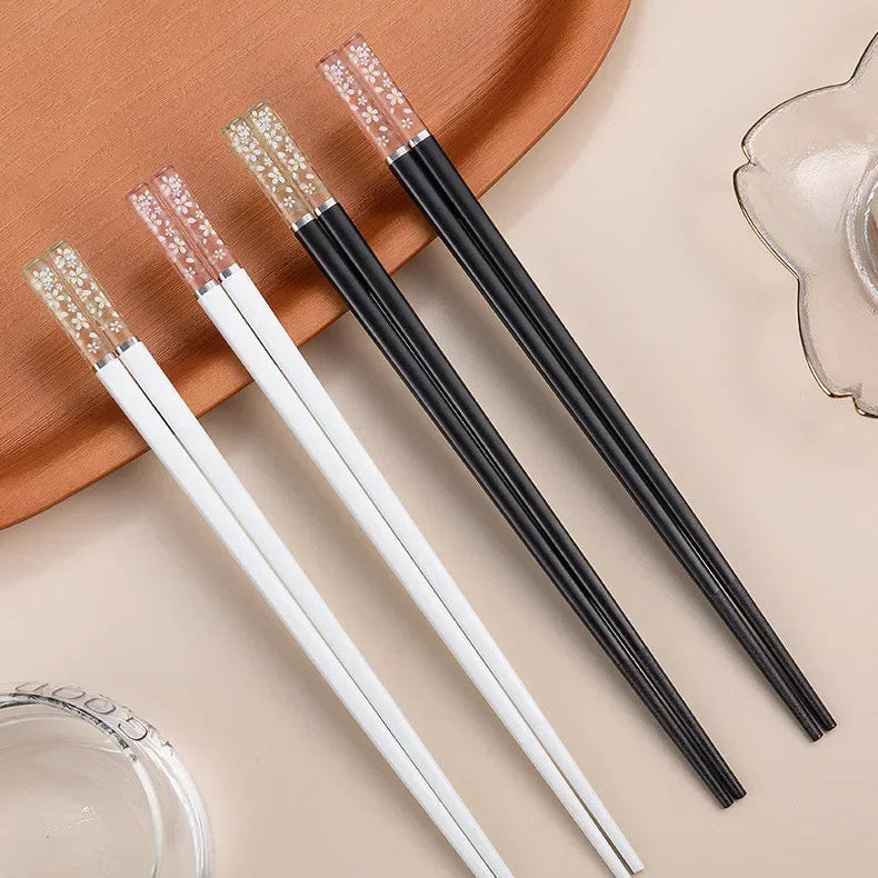 Set of black and white kawaii chopsticks on a beige surface with a brown plate in the background.