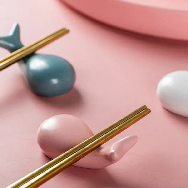 Gold kawaii chopstick holders on a pink surface with decorative elements