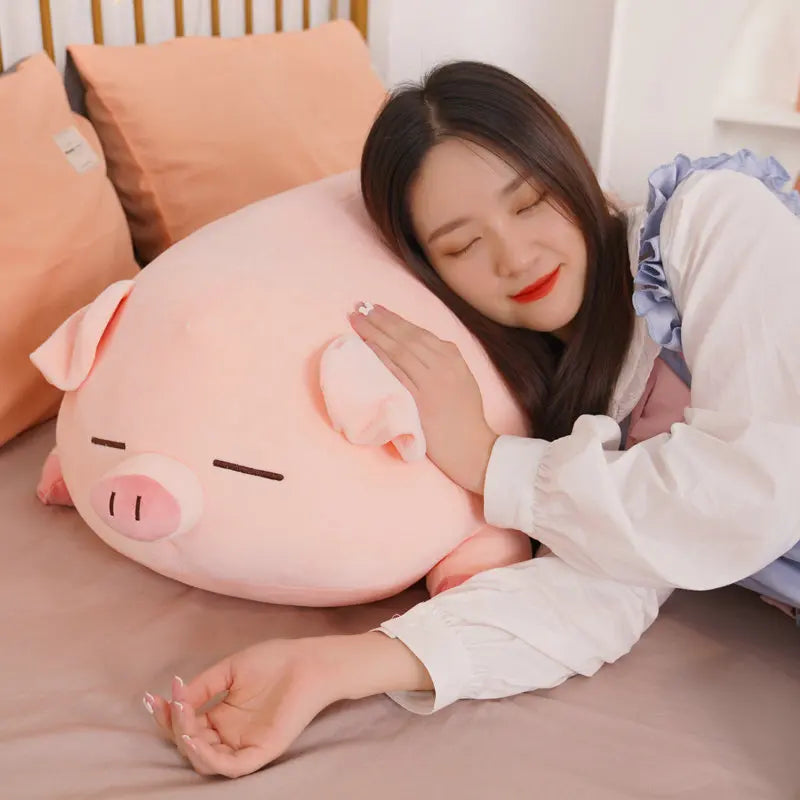 Woman hugging a large kawaii pink pig-shaped pillow on a bed.