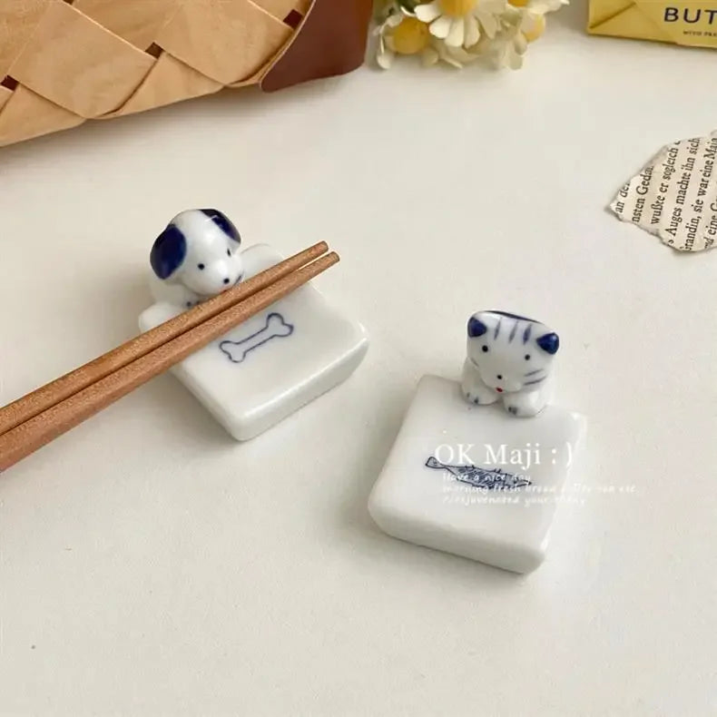 Two small ceramic kawaii chopstick holders with animal designs and chopsticks on a light surface.