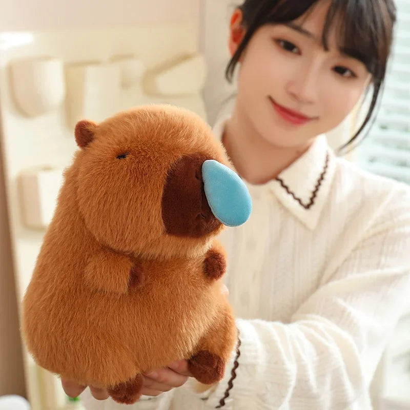 Person holding a kawaii plush toy resembling a brown animal with a blue nose.