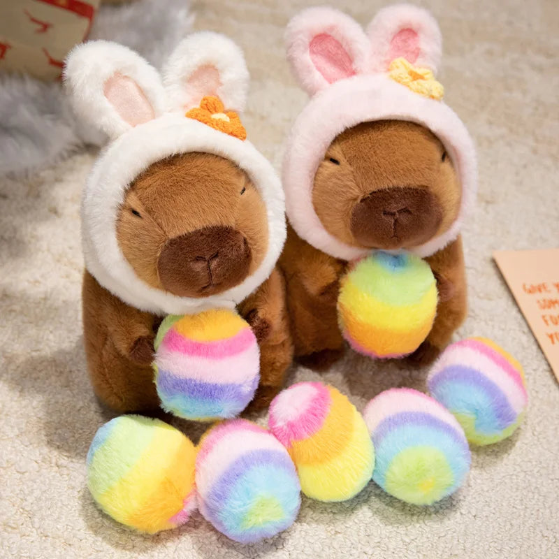 Two kawaii plush toys with bunny ears and colorful balls on a soft surface