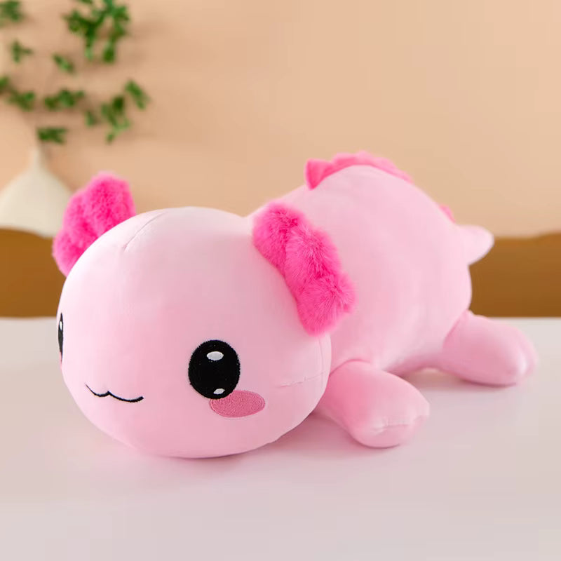 Pink plush axolotl toy on a light surface with a blurred background