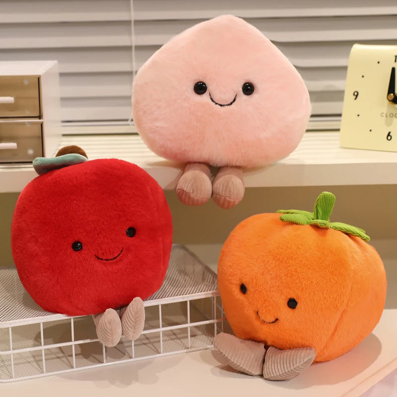 Three kawaii plush toys shaped like a red apple, pink peach, and orange pumpkin on a shelf.