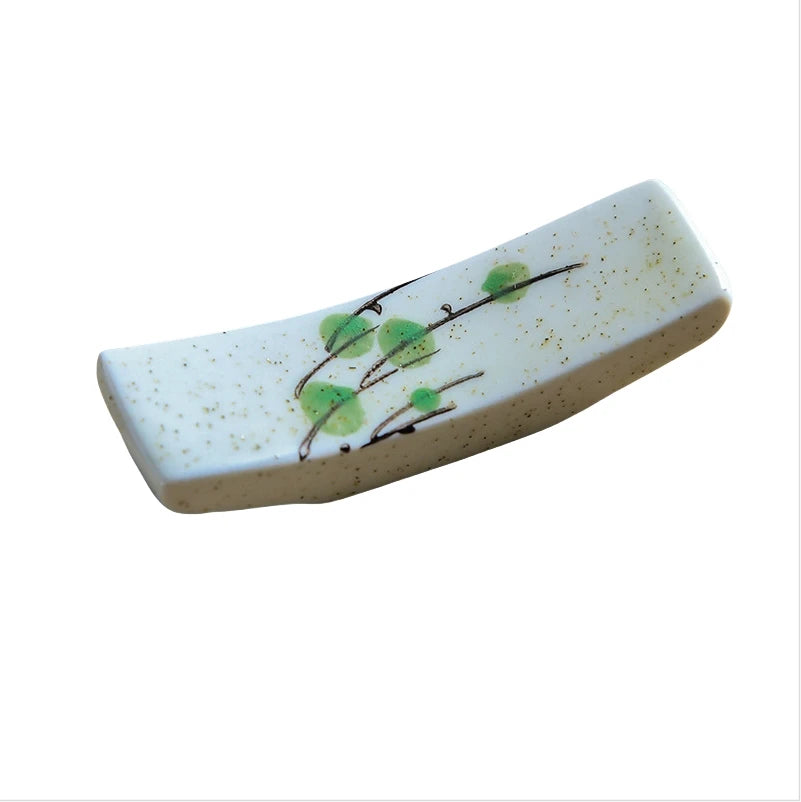 Rectangular ceramic kawaii chopstick holder with green leaf design on a white background