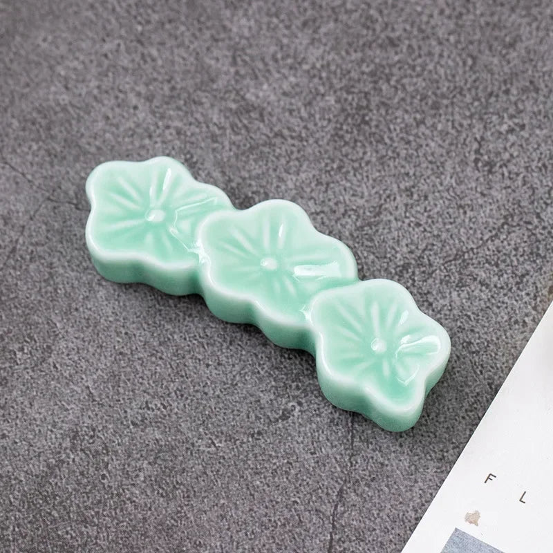 Light green ceramic flower-shaped kawaii chopstick holder on a gray surface