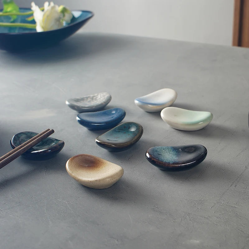 Set of ceramic kawaii chopstick holders with different finishes on a gray surface