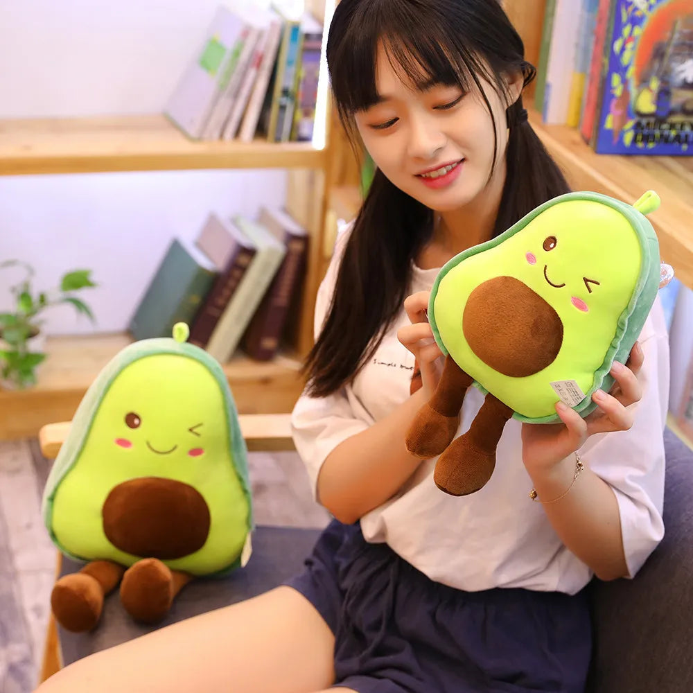 Person holding two avocado-shaped kawaii plush toys in a room with books and plants.