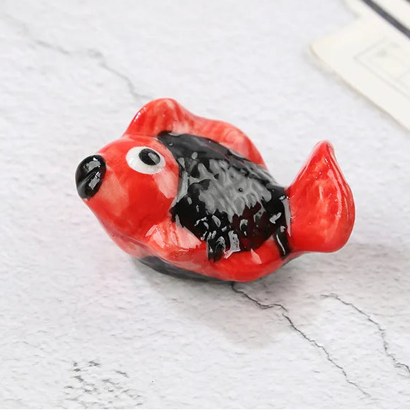 Small red and black fish-shaped kawaii chopstick holders on a light gray surface with text indicating dimensions.
