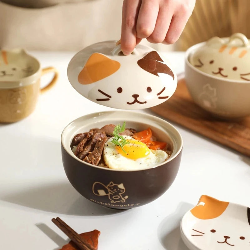 Cute cat-shaped kawaii ramen bowls being placed on a bowl of food with more cat-themed bowls in the background.