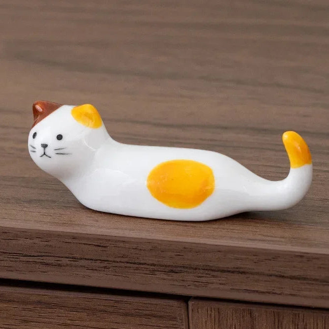 Cat-shaped kawaii chopstick holders with yellow spots on a wooden surface
