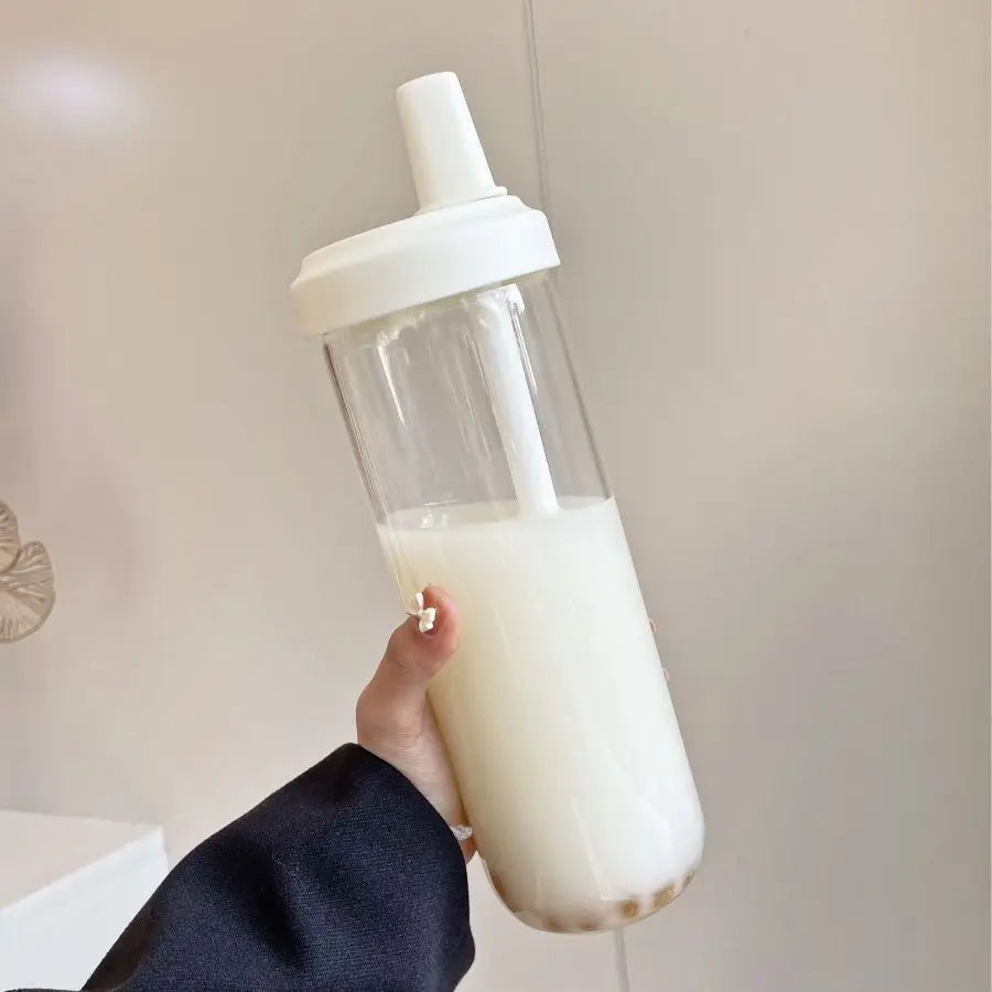 Clear kawaii water bottle with white cap filled with a white liquid, held by a person.
