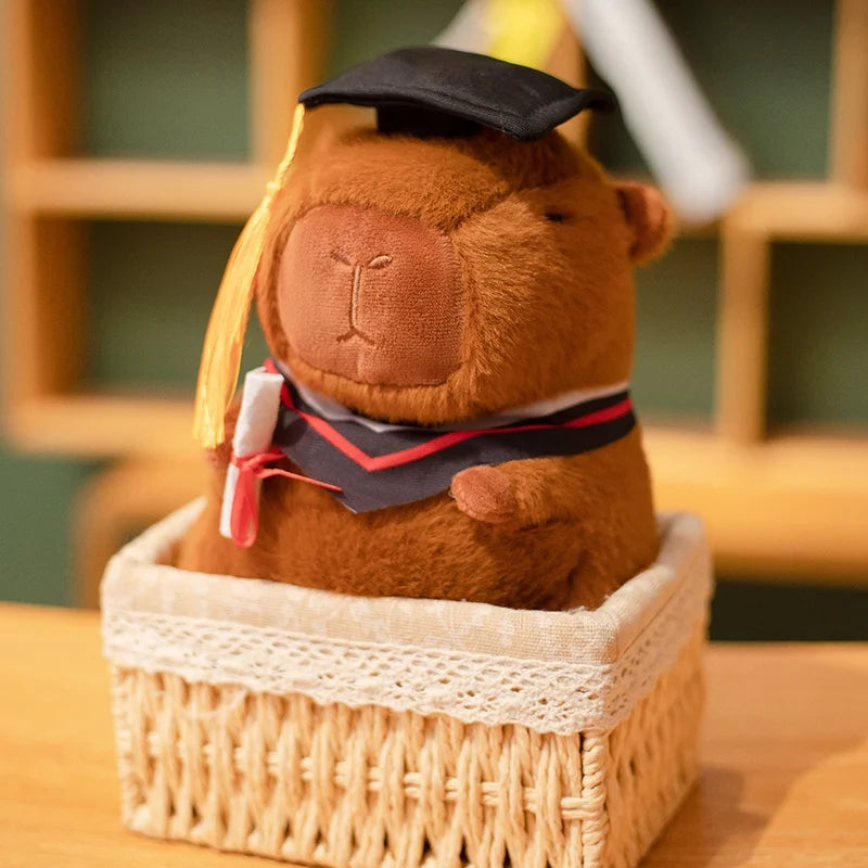 Capybara plush toy in a graduation cap and gown sitting in a woven basket.