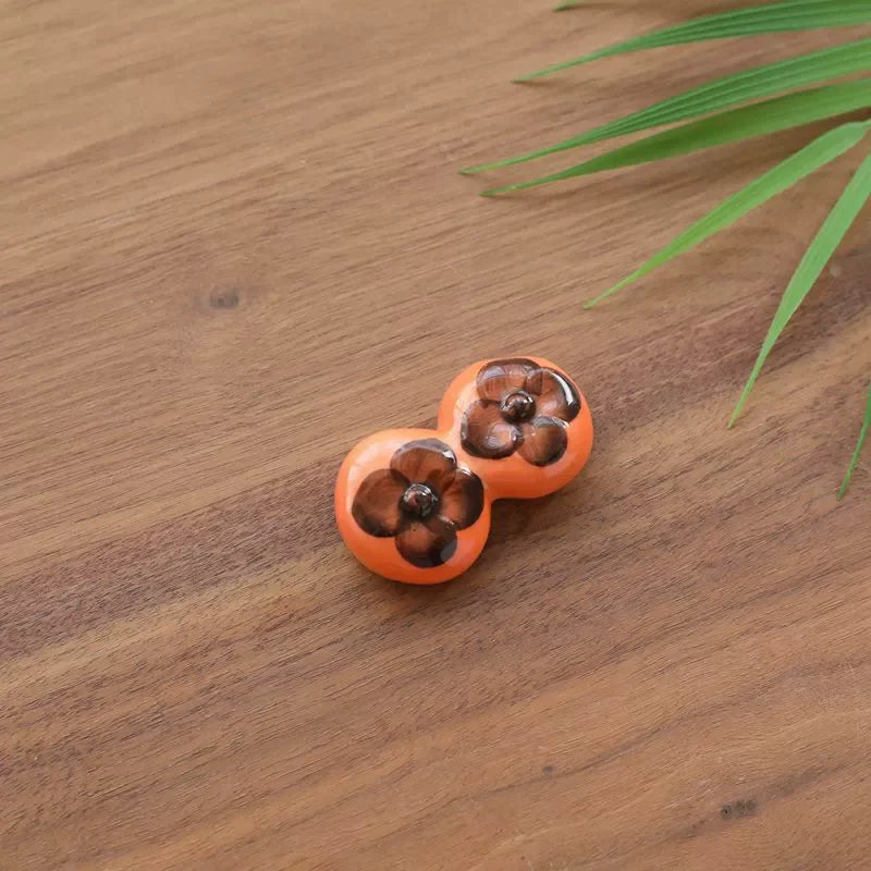 Pair of orange kawaii earrings with brown centers on a wooden surface