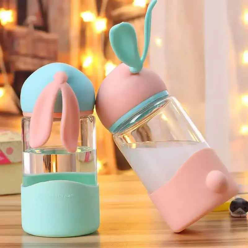 Two kawaii bottles with colorful silicone covers on a wooden surface.