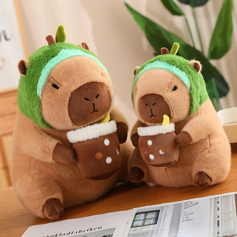 Two kawaii plush toys resembling animals with green hats holding hot chocolate cups on a wooden surface.
