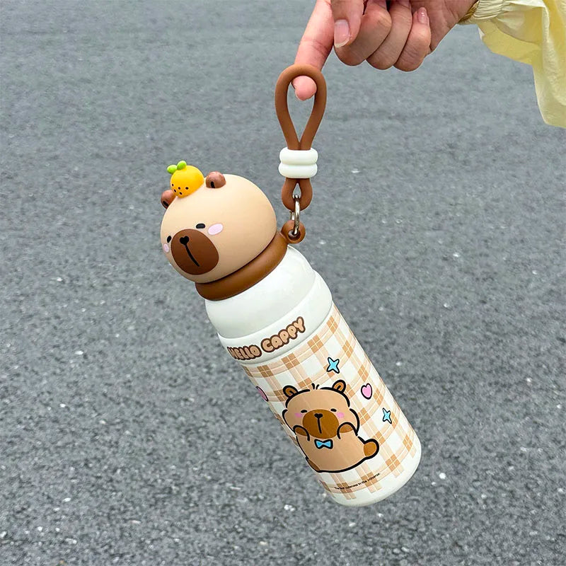 Cute bear-themed kawaii water bottle with keychain on a gray pavement background