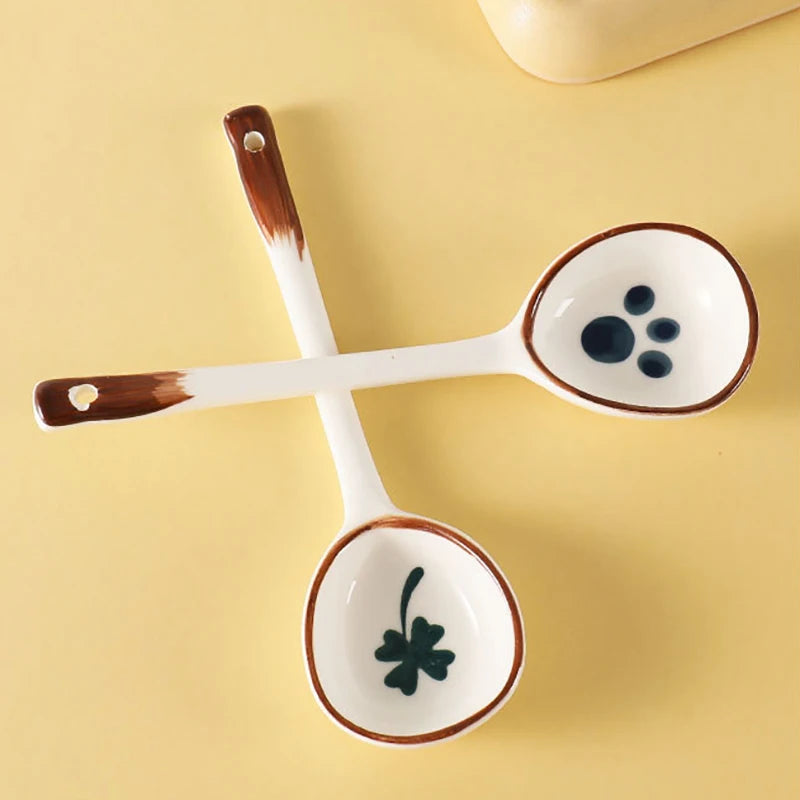 Two white ceramic kawaii spoons behind a yellow background