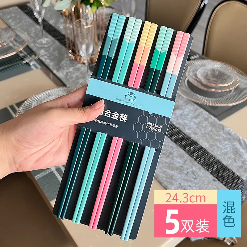 Pack of colorful kawaii chopsticks held by a hand with a dining table setting in the background