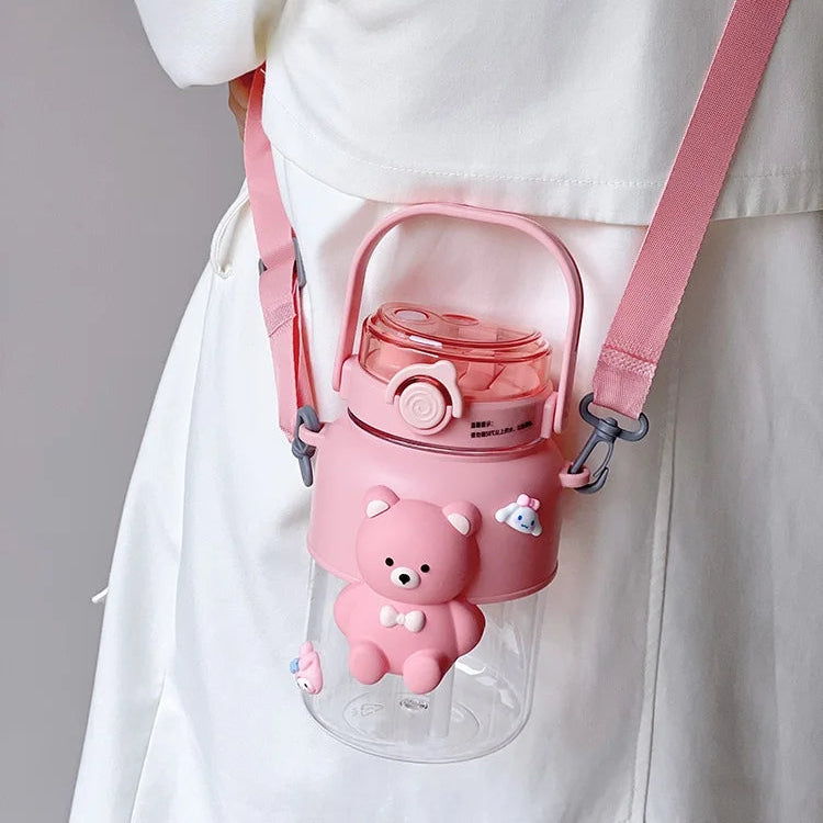 Pink kawaii water bottle with bear design attached to a pink strap over a white outfit.