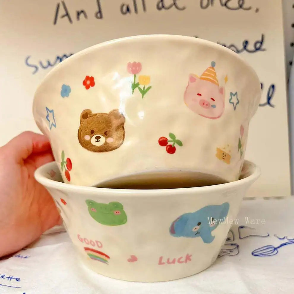 Ceramic kawaii ramen bowl with cartoon designs held by a hand, with a white background.