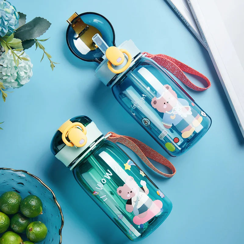 Two cartoon-themed kawaii water bottles on a blue surface with a bowl of limes and flowers.