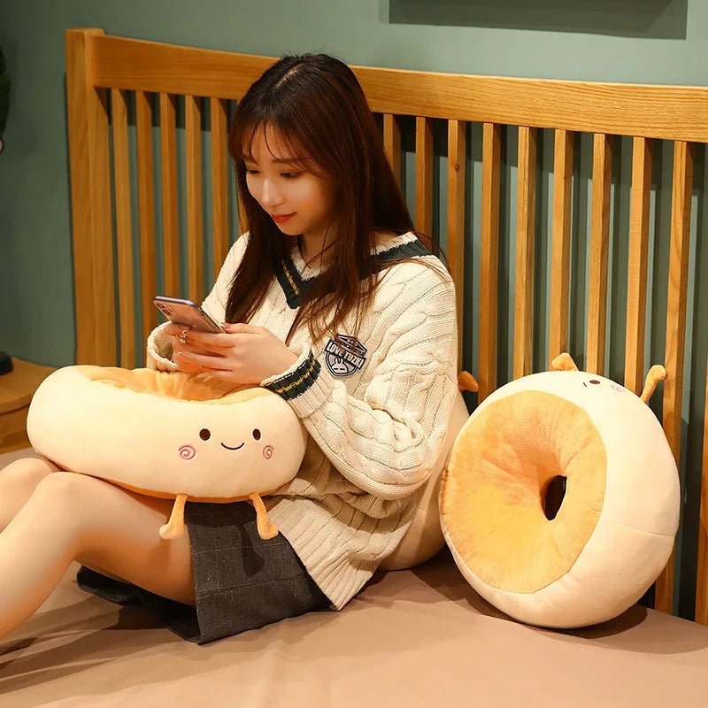 Woman sitting on a bed with two kawaii plush donut-shaped pillows and a smartphone.