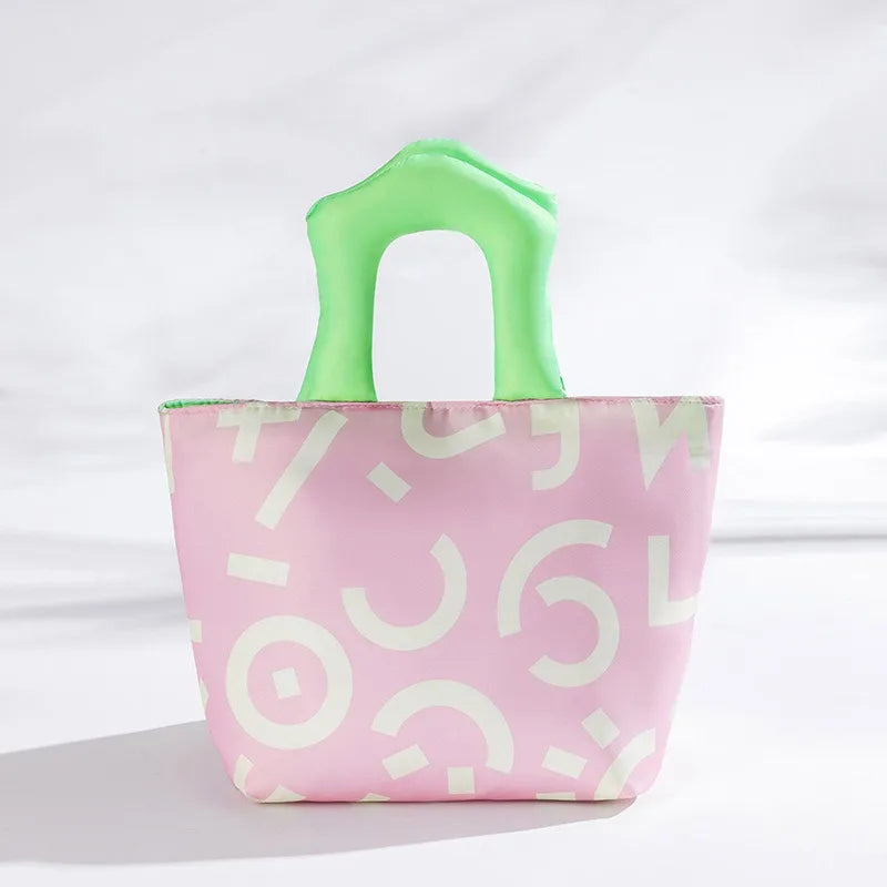 Pink kawaii tote bag with white patterns and green handles on a light gray background