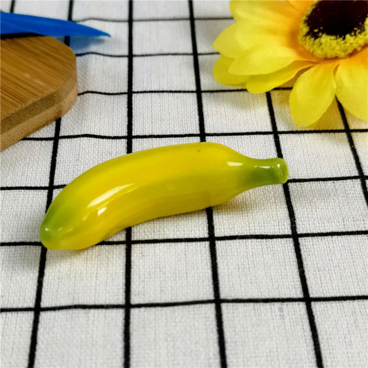 Yellow banana-shaped kawaii chopstick holders on a grid-patterned surface with a sunflower and wooden item in the background.