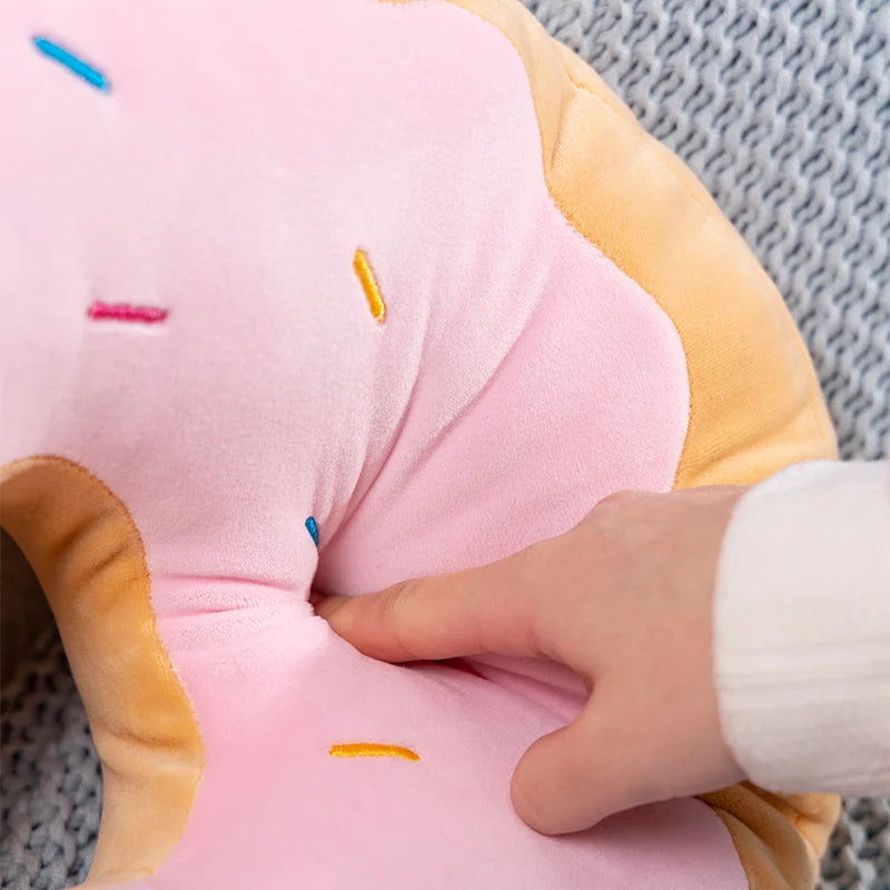 Close-up of a pink kawaii plush toy with a hand interacting with it on a textured surface.