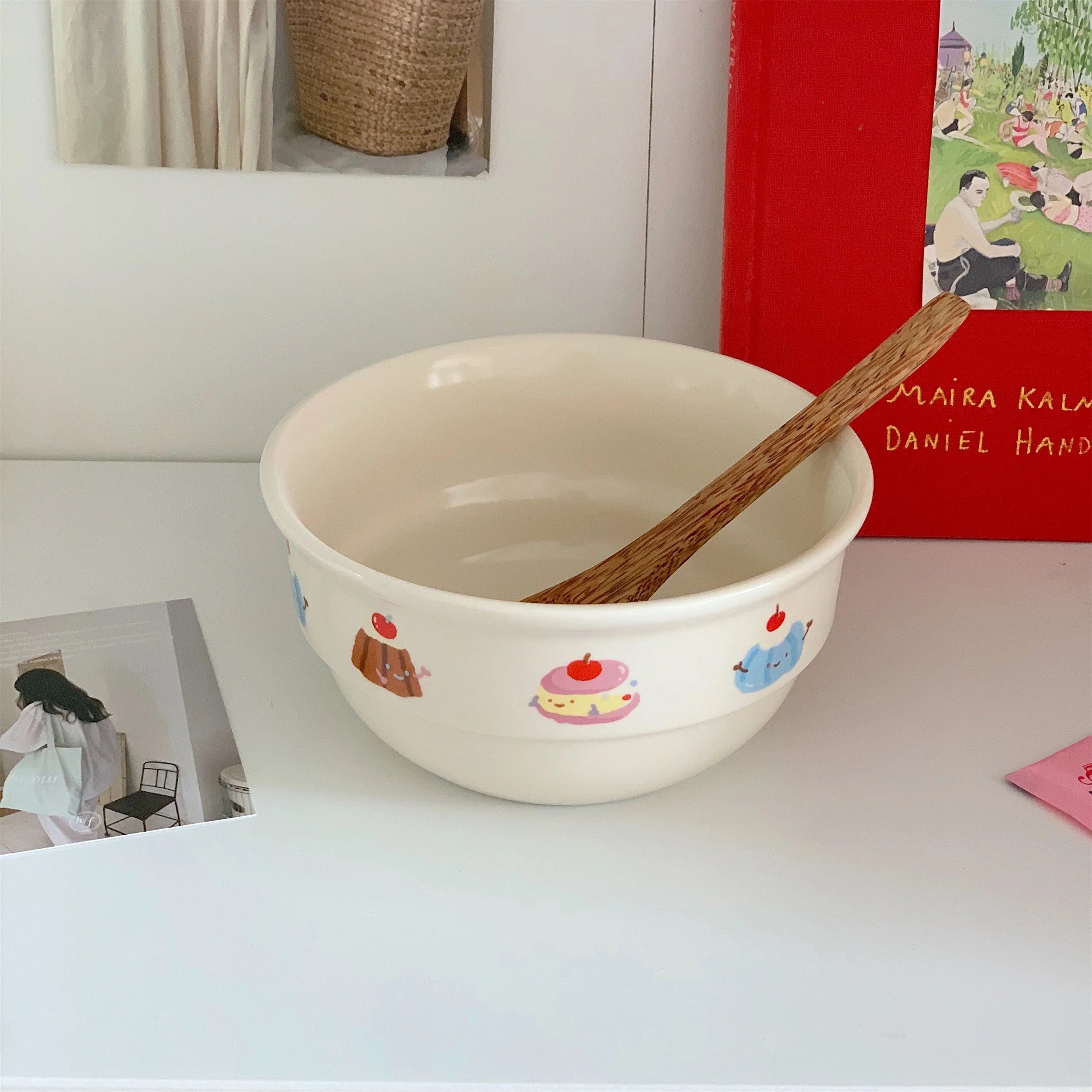 White kawaii ramen bowl with cartoon illustrations on a white surface, containing a wooden spoon.