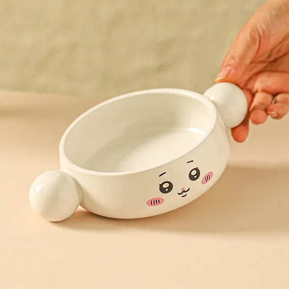 Ceramic kawaii ramen bowl with cartoon face design held by a hand on a beige background