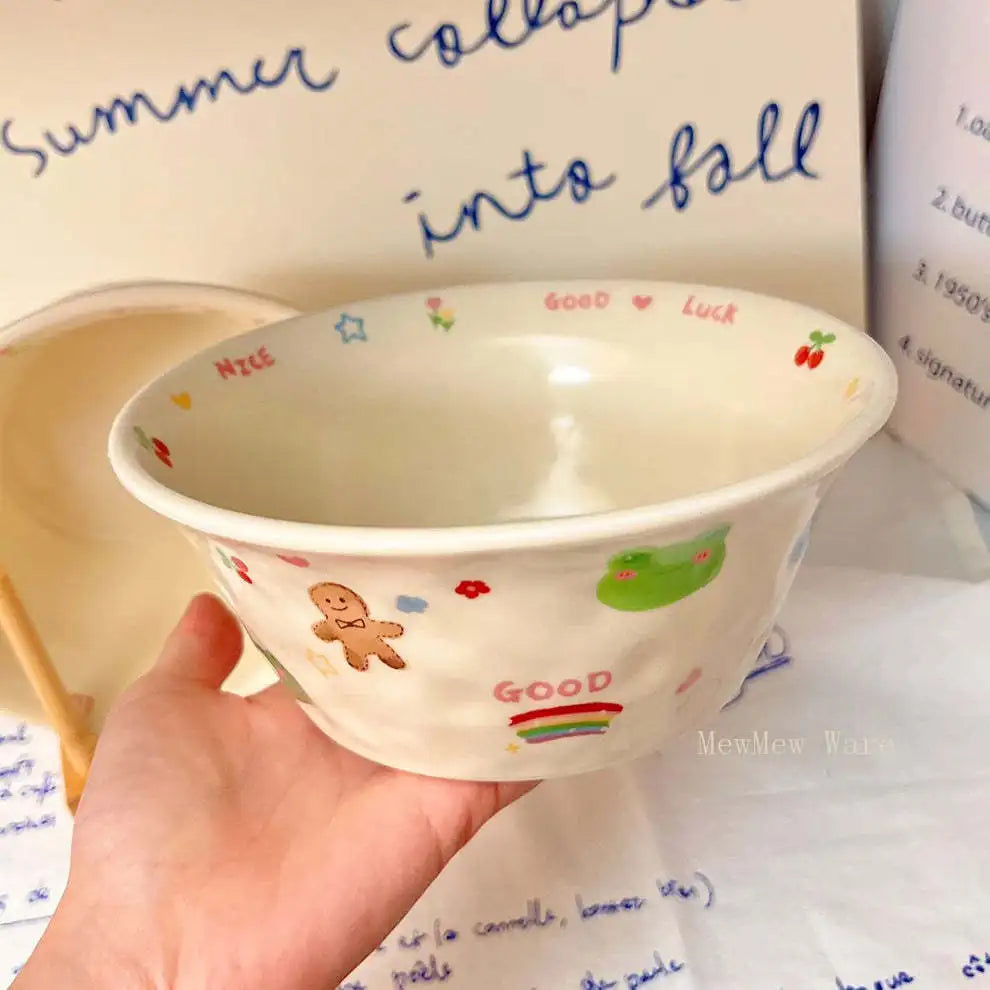 Hand holding a small white kawaii ramen bowl with colorful designs against a background of text.