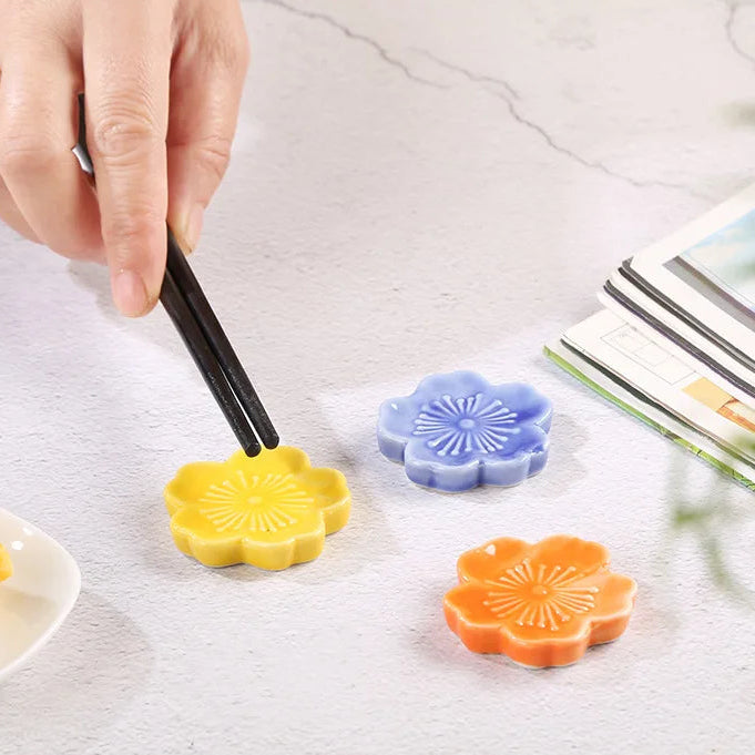 A person placing chopsticks on a yellow kawaii chopstick holder