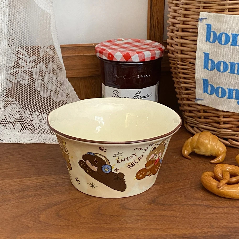 Ceramic kawaii ramen bowl with cartoon designs on a wooden surface, next to a jar of jam and a basket.