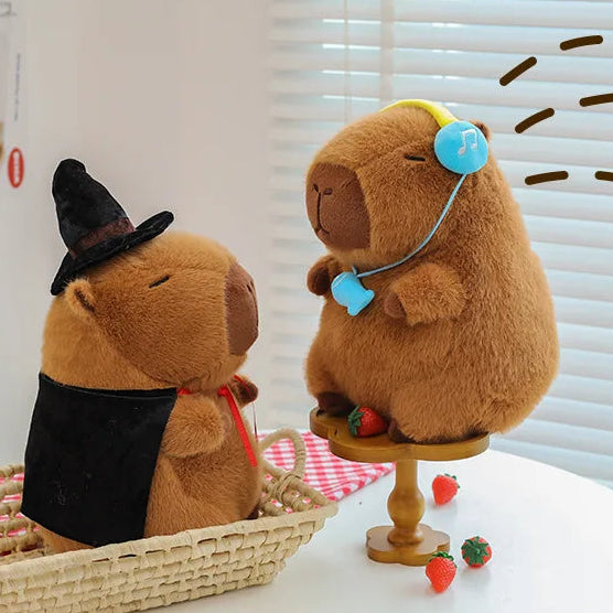 Two capybara plush toys, one in a witch costume and the other with a stethoscope, on a table with a white background.