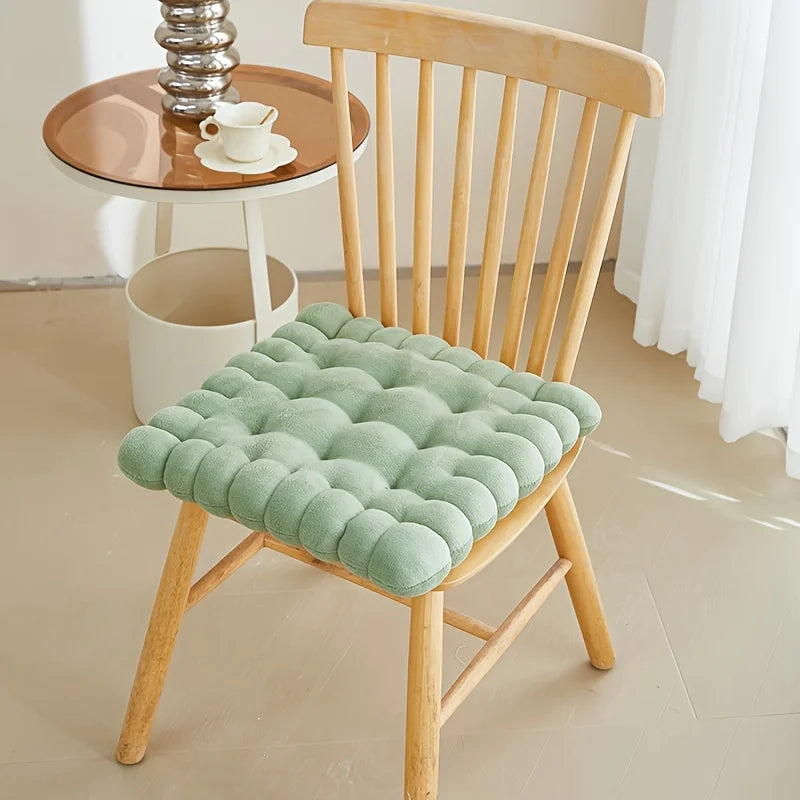 Green kawaii cushion on a wooden chair with a small table and decor items in the background.