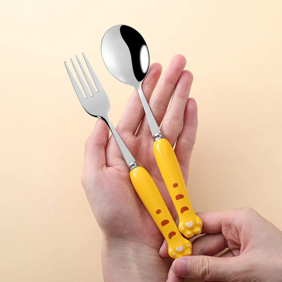 A person holding yellow, paw shaped kawaii utensils