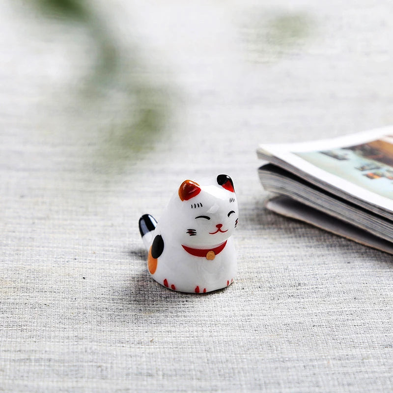 Small ceramic kawaii cat figurine on a textured surface with a blurred background