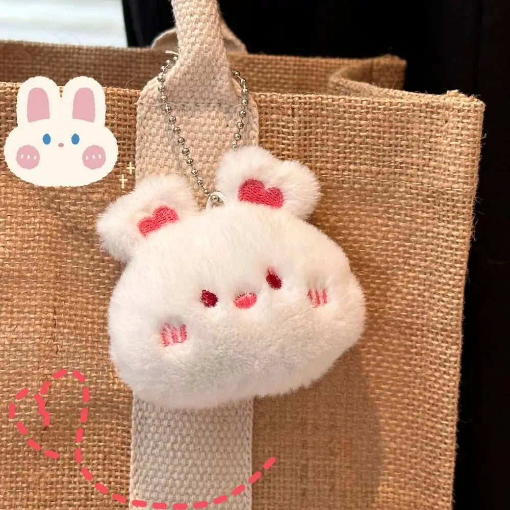 Fluffy white kawaii keychain with pink accents on a brown textured background
