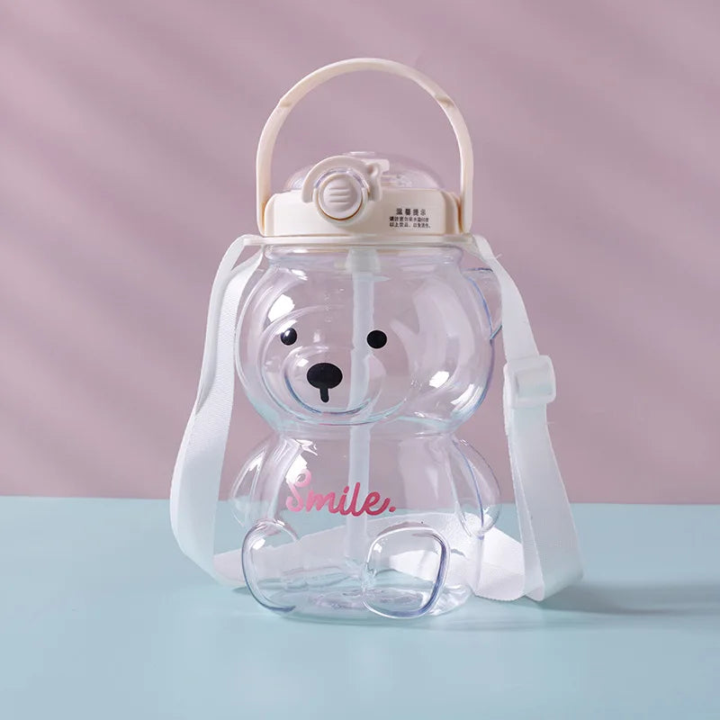 Clear bear-shaped kawaii water bottle with a handle on a light blue surface and pink background