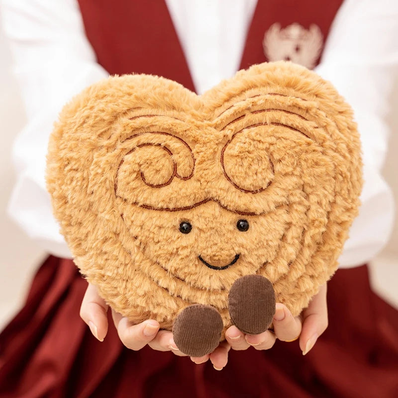 Heart-shaped kawaii plush toy with a face held by a person wearing a red apron.