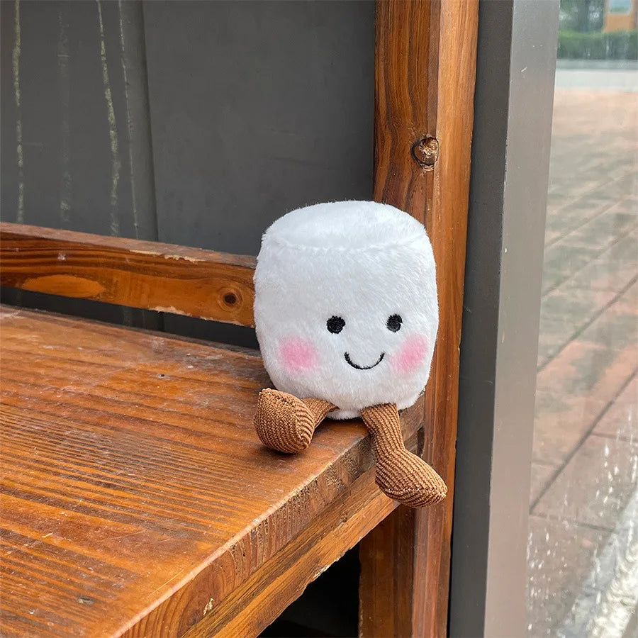Kawaii plush toy resembling a marshmallow with a smiling face on a wooden surface.